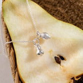 A miniature silver Lemon charm and Pear  charm on a silver rolo chain.